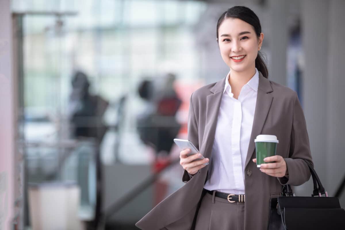 asian woman with smartphone standing against street blurred building fashion business photo beautiful girl casual suite with phone cup coffee